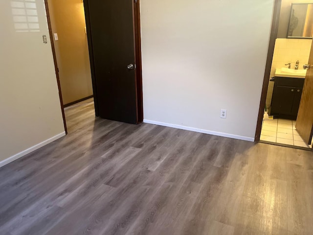 unfurnished bedroom featuring sink, ensuite bath, and light wood-type flooring