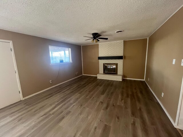 unfurnished living room featuring a textured ceiling, a fireplace, dark hardwood / wood-style floors, and ceiling fan