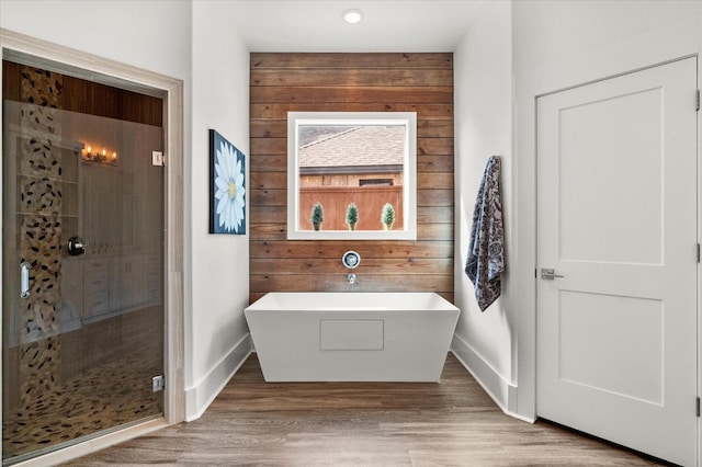 bathroom featuring independent shower and bath, hardwood / wood-style floors, and wooden walls