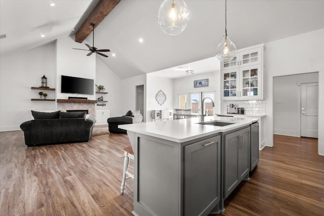 kitchen with gray cabinets, pendant lighting, sink, a center island with sink, and beam ceiling