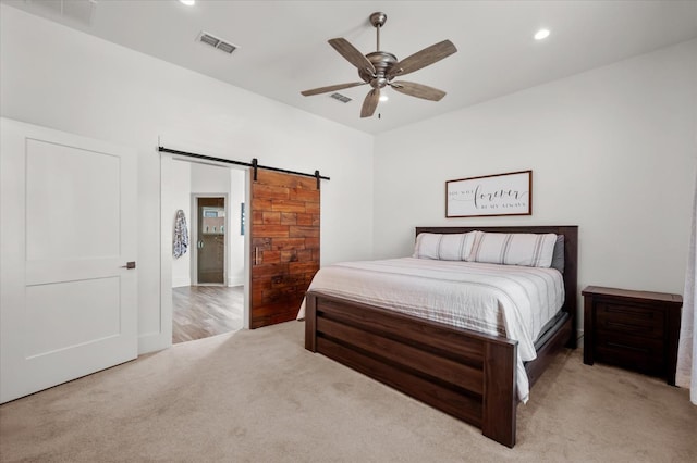 bedroom featuring a barn door, light carpet, and ceiling fan