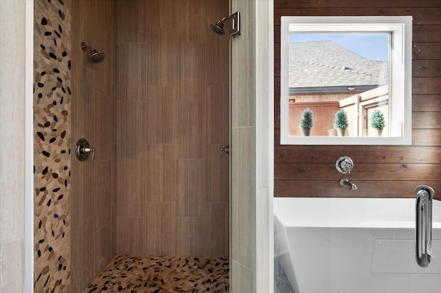 bathroom featuring wooden walls, a healthy amount of sunlight, and plus walk in shower