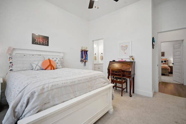 carpeted bedroom with a high ceiling, connected bathroom, and ceiling fan