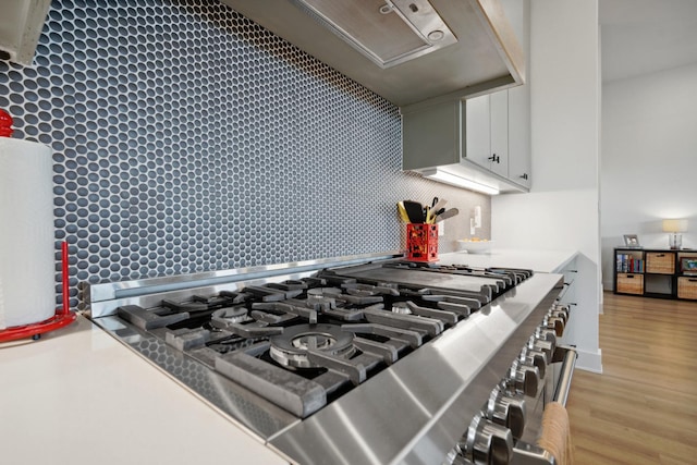 details with white cabinetry, backsplash, light hardwood / wood-style flooring, and cooktop