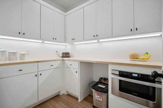 kitchen featuring white cabinetry, oven, and light wood-type flooring