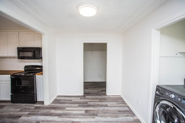 kitchen with butcher block counters, washer / clothes dryer, light hardwood / wood-style flooring, and black appliances