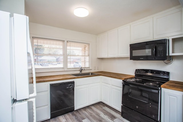 kitchen featuring white cabinetry, butcher block counters, sink, and black appliances