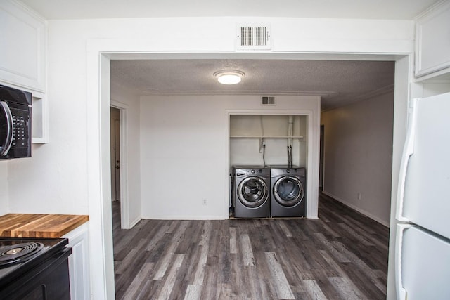 clothes washing area with washer and clothes dryer, dark hardwood / wood-style floors, and a textured ceiling