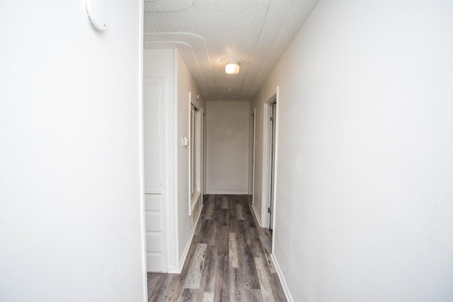 corridor with wood-type flooring and a textured ceiling