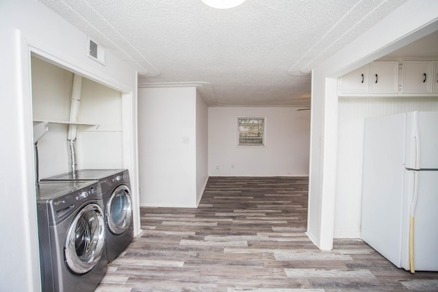 laundry area with separate washer and dryer, light hardwood / wood-style flooring, and a textured ceiling