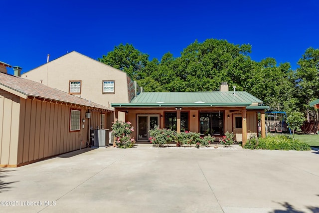 5412 20th St, Lubbock, TX 79407 - view of front of home featuring cooling unit, a chimney, a porch, a standing seam roof, and board and batten siding