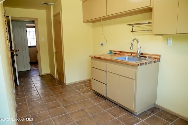5412 20th St, Lubbock, TX 79407 - kitchen featuring a sink, baseboards, cream cabinets, and tile patterned flooring