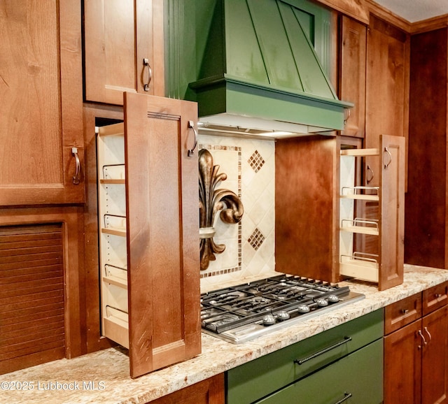 5412 20th St, Lubbock, TX 79407 - kitchen featuring premium range hood, stainless steel gas stovetop, backsplash, green cabinets, and light stone counters