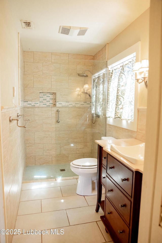 5412 20th St, Lubbock, TX 79407 - full bathroom featuring a stall shower, toilet, tile patterned flooring, vanity, and tile walls