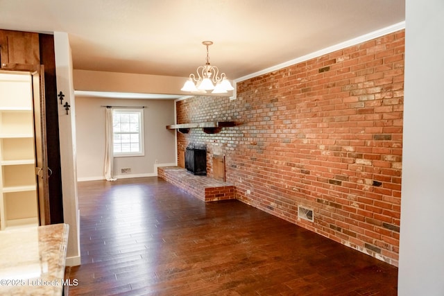 5412 20th St, Lubbock, TX 79407 - unfurnished living room with dark wood-style flooring, a brick fireplace, brick wall, baseboards, and a chandelier