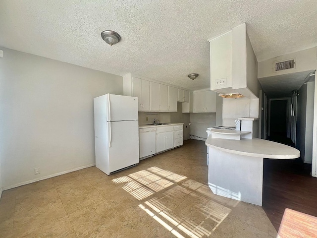 kitchen with sink, a breakfast bar area, white cabinetry, a textured ceiling, and white appliances