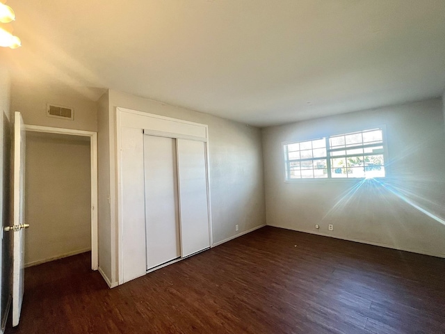 unfurnished bedroom featuring dark wood-type flooring and a closet