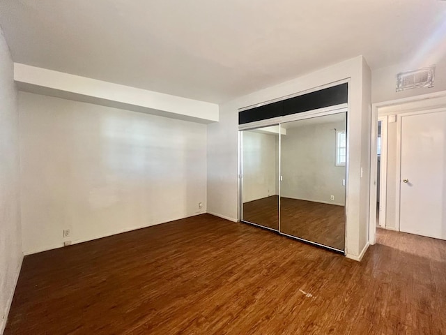 unfurnished bedroom featuring wood-type flooring and a closet