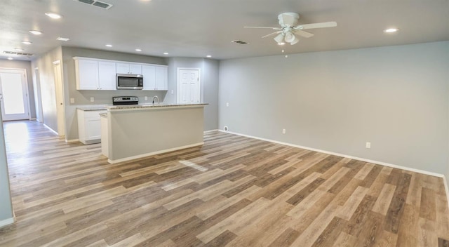 kitchen with stainless steel appliances, a kitchen island with sink, white cabinets, and light hardwood / wood-style flooring