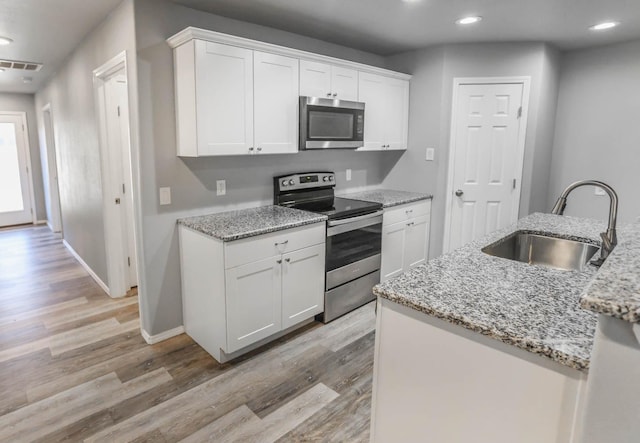 kitchen featuring white cabinetry, appliances with stainless steel finishes, light stone countertops, and sink