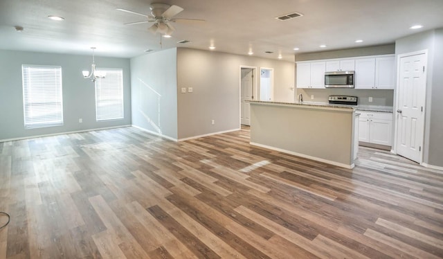 kitchen with appliances with stainless steel finishes, decorative light fixtures, white cabinetry, light hardwood / wood-style floors, and a center island with sink