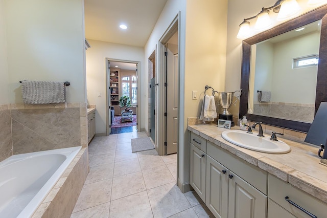 bathroom featuring vanity, tiled tub, and tile patterned flooring