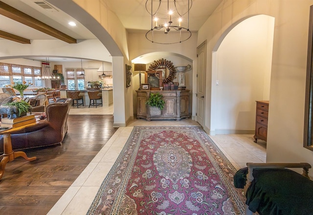 interior space featuring beamed ceiling, light hardwood / wood-style floors, and a chandelier