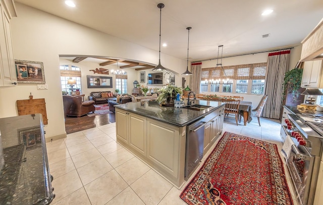 kitchen featuring a kitchen island with sink, sink, stainless steel appliances, and a chandelier