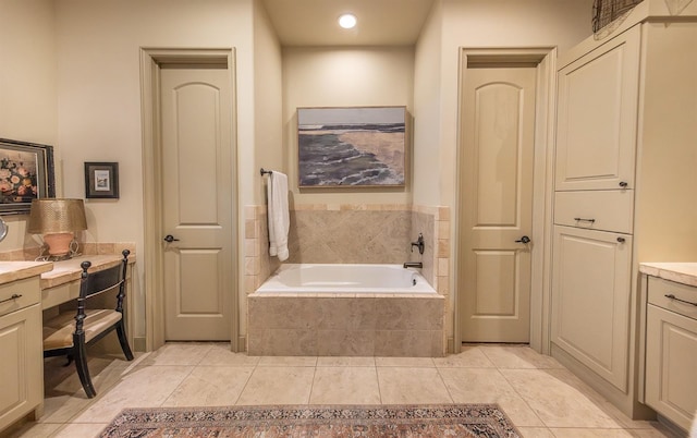 bathroom featuring tiled tub, vanity, and tile patterned floors