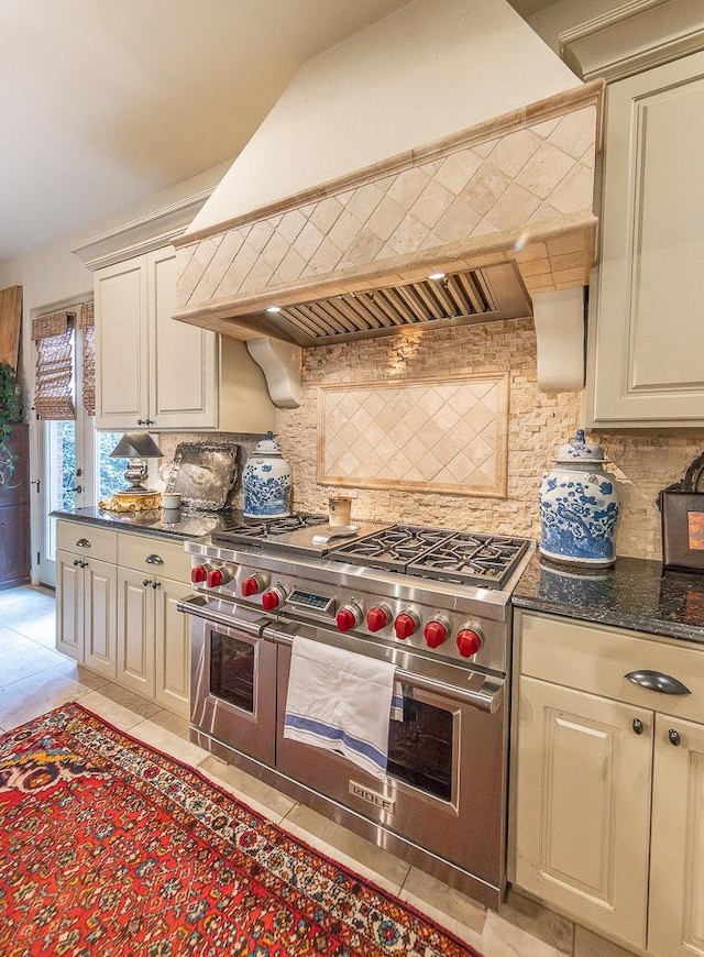 kitchen featuring backsplash, cream cabinets, premium range hood, and range with two ovens