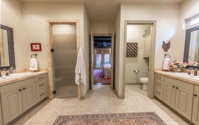 bathroom with a shower with door, vanity, tile patterned floors, and toilet