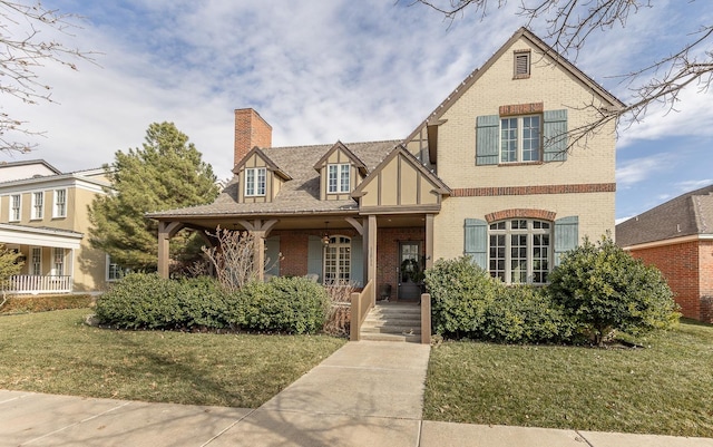 tudor home featuring a porch and a front yard