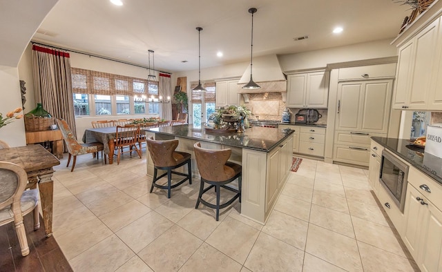 kitchen with a kitchen island, stainless steel microwave, decorative light fixtures, backsplash, and a kitchen breakfast bar