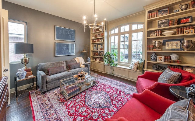 living room with built in features, dark hardwood / wood-style floors, a notable chandelier, and ornamental molding