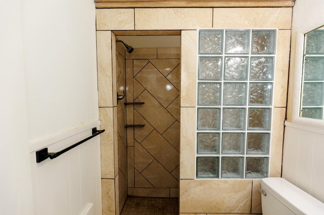 bathroom with a tile shower and toilet