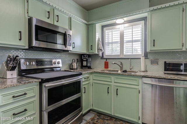 2608 74th Pl, Lubbock, TX 79423 - kitchen featuring appliances with stainless steel finishes, green cabinetry, decorative backsplash, and light stone counters