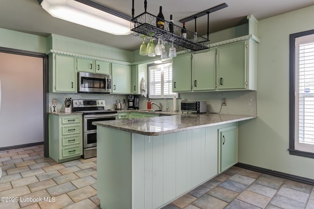 2608 74th Pl, Lubbock, TX 79423 - kitchen with green cabinets, stainless steel appliances, a peninsula, and tasteful backsplash