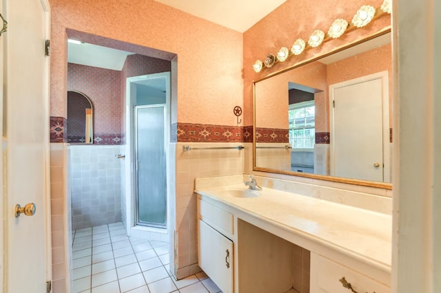 bathroom with tile walls, vanity, a shower with shower door, and tile patterned floors