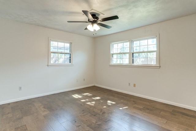 spare room with dark wood-type flooring, ceiling fan, and plenty of natural light