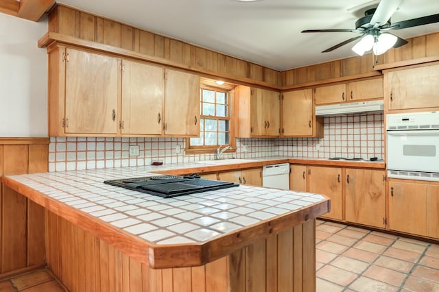 kitchen featuring tasteful backsplash, white appliances, tile counters, and kitchen peninsula