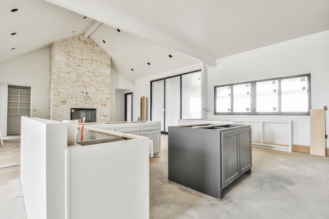 kitchen with gray cabinets, high vaulted ceiling, a fireplace, a center island, and beam ceiling