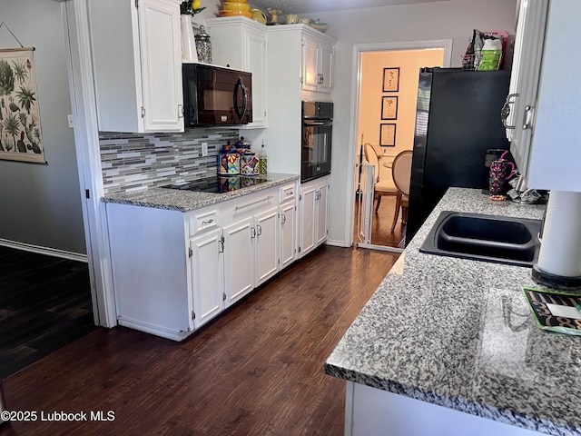 kitchen featuring white cabinets, dark wood finished floors, baseboards, black appliances, and tasteful backsplash