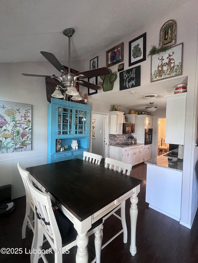 dining space featuring dark wood finished floors, a ceiling fan, and a textured ceiling