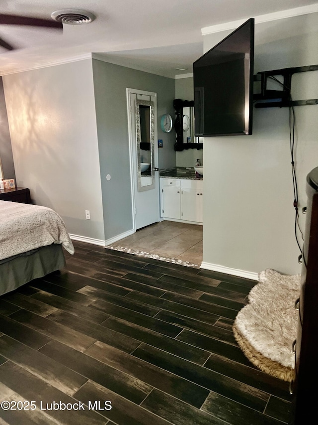 bedroom featuring baseboards, ornamental molding, visible vents, and wood finished floors