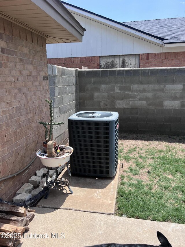 details with central AC unit, brick siding, and fence