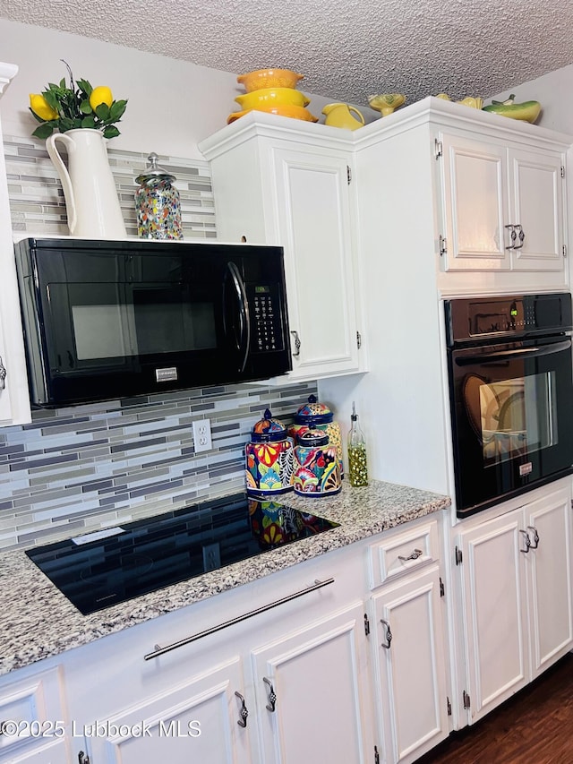 kitchen featuring light stone counters, backsplash, black appliances, and white cabinets