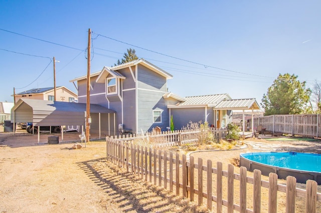 back of house featuring a fenced in pool and a carport