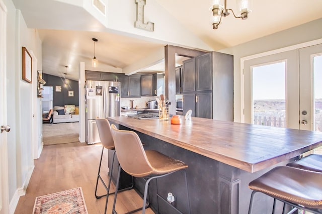 kitchen with lofted ceiling, pendant lighting, stainless steel appliances, and a kitchen bar