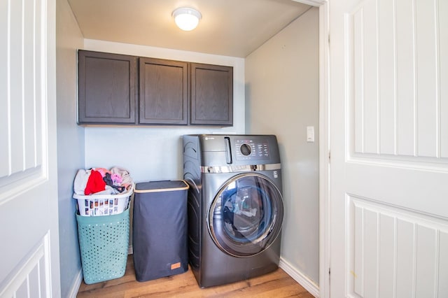 clothes washing area featuring washer / clothes dryer, light hardwood / wood-style flooring, and cabinets