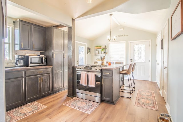 kitchen featuring lofted ceiling, a breakfast bar area, a center island, pendant lighting, and stainless steel appliances